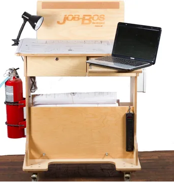 A wooden desk with “JOB BOS,” a laptop, a lamp, and a fire extinguisher